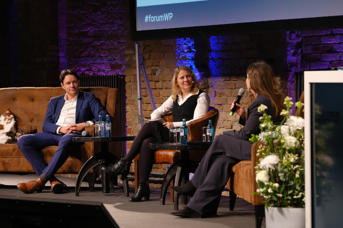 Moderatorin Tina Teucher auf der Bühne mit zwei Gästen des Forum Wärmepumpe 2025 in Berlin