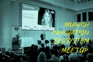 Tina Teucher moderiert auf Bühne. Text auf Bild: Munich Innovation Ecosystem Meetup