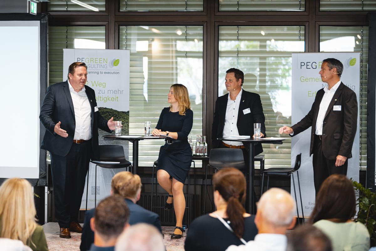 Tina Teucher moderiert Podiumsgespräch zwischen drei Männern beim PEG Fachsymposium für Nachhaltigkeit im Gesundheitswesen