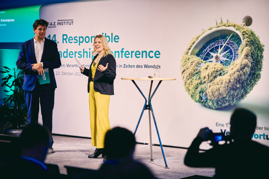 Tina Teucher steht neben einem Mann auf der Bühne der Responsible Leadership Conference
