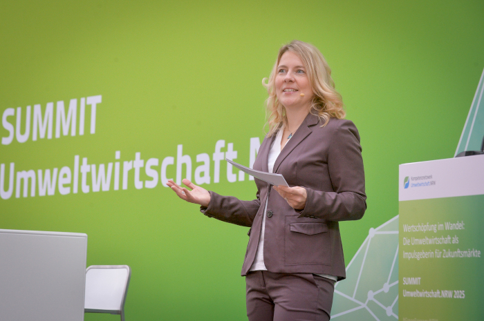 Tina Teucher moderiert vor einer grünen Leinwand