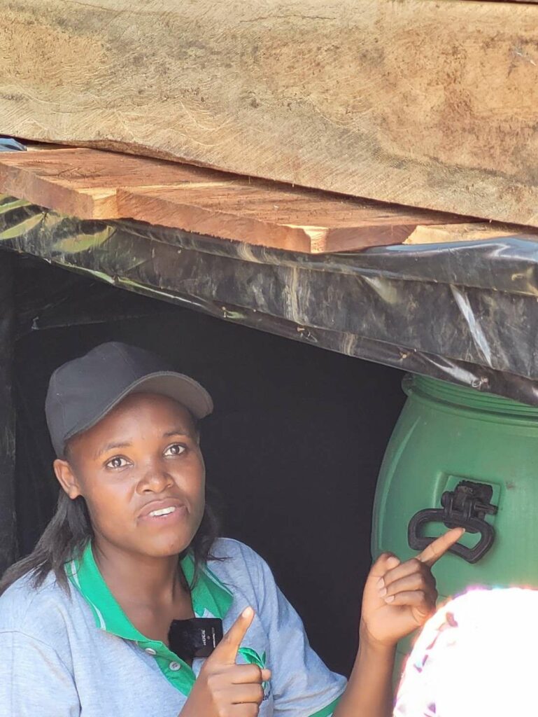 Winnie Tushabe, YICE co-founder and implementation director in front of compost toilet Ecosan