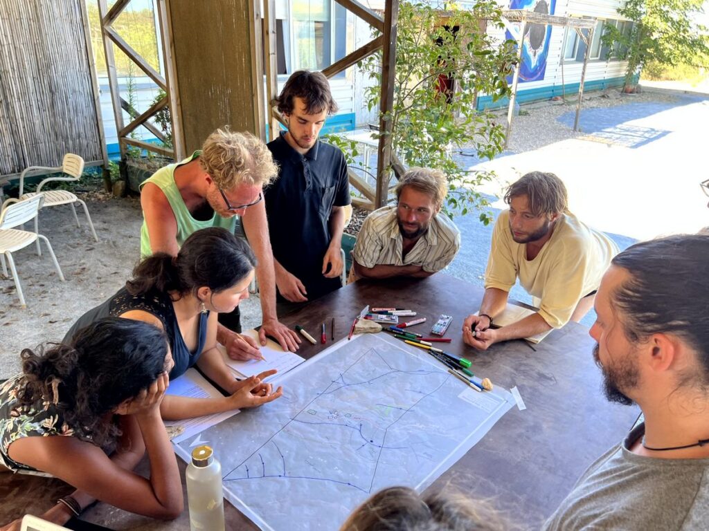 Eine Gruppe von Menschen bespricht eine Landschaftsskizze, die vor ihnen auf einem Tisch liegt